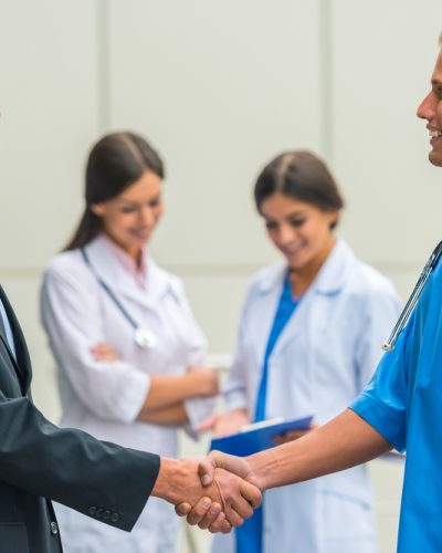 Patron. Senior male businessman shakes hands doctors in hospital